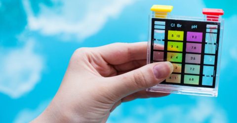 checking pH level in blue outdoor pool by chemical tester
