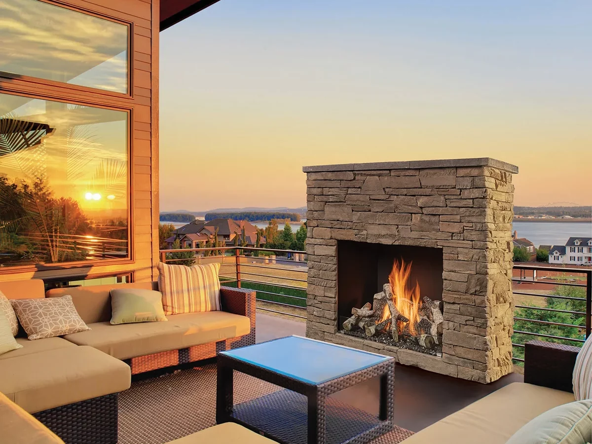 A traditional gas fireplace on an outdoor patio at sunset