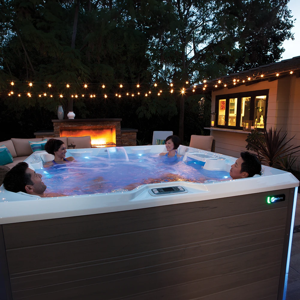 Four adults sitting a Hot Spring Limelight. Pulse hot tub