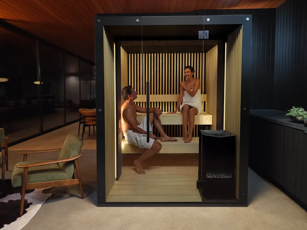 Two people sitting inside a Tylo sauna in a dimly lit room